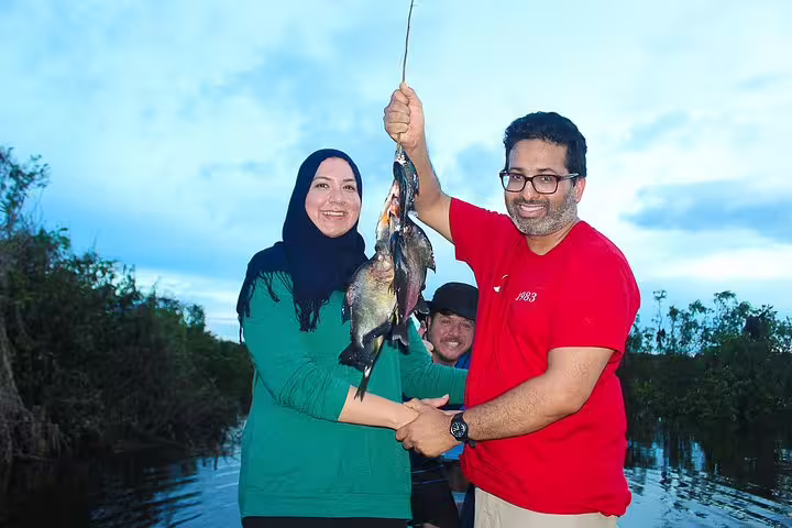 Tourists enjoying fishing at Amazon Tapiri Floating Lodge with a fresh catch in the vibrant Amazon jungle.