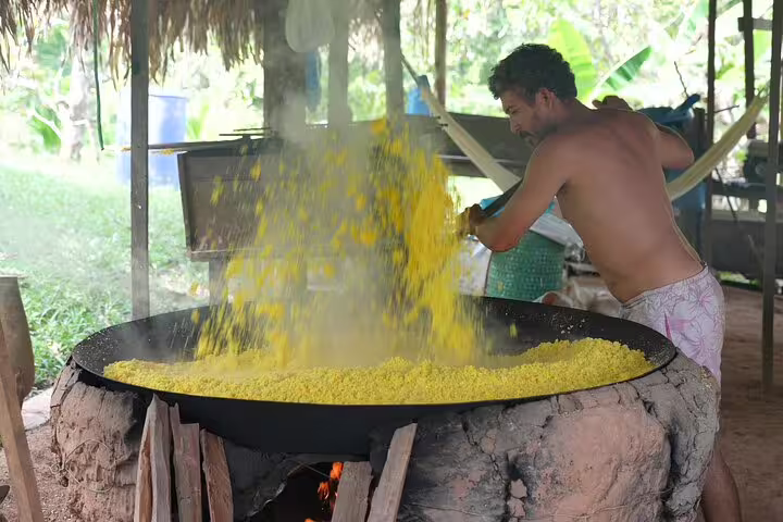 Local Amazonian man stirs yellow manioc flour over a traditional stove, depicting cultural experiences on the jungle tour.