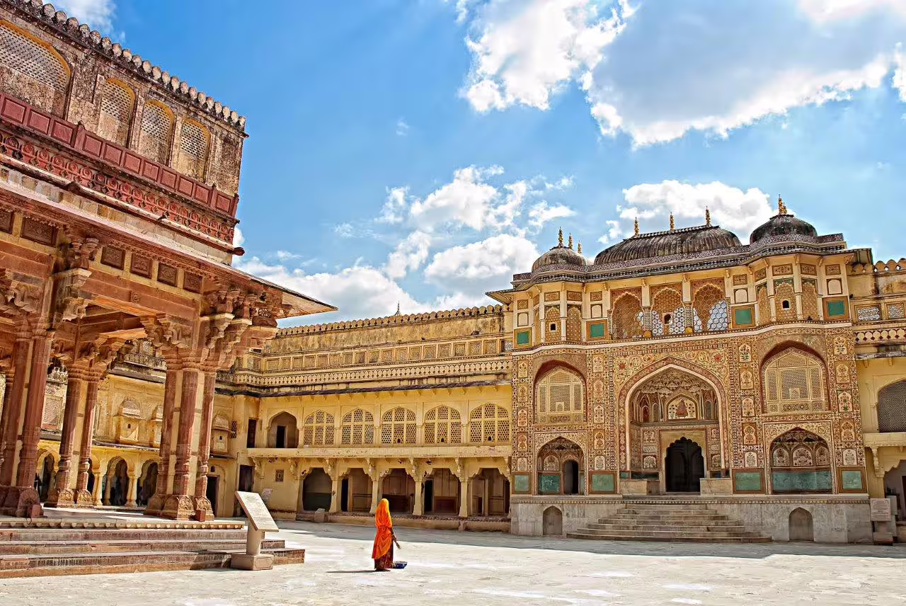 Marvel at the intricate designs of Amber Fort's courtyard under a clear blue sky during the Rajasthan tour.