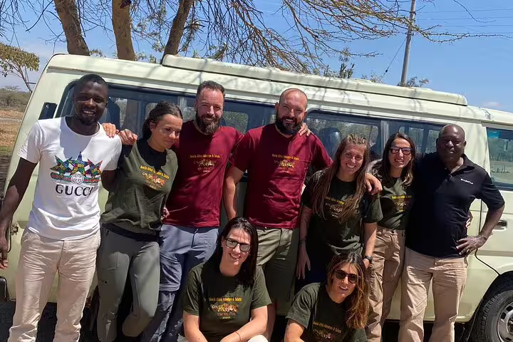 Group of tourists ready for 2 Days 1 Night Amboseli Safari from Nairobi with safari vehicle in background.