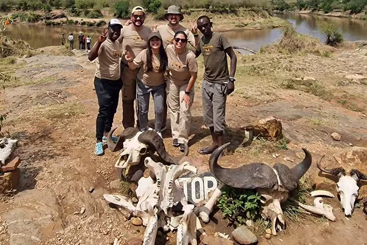 Group of safari tourists posing with animal skulls in Amboseli National Park during a 2-day Nairobi safari tour.