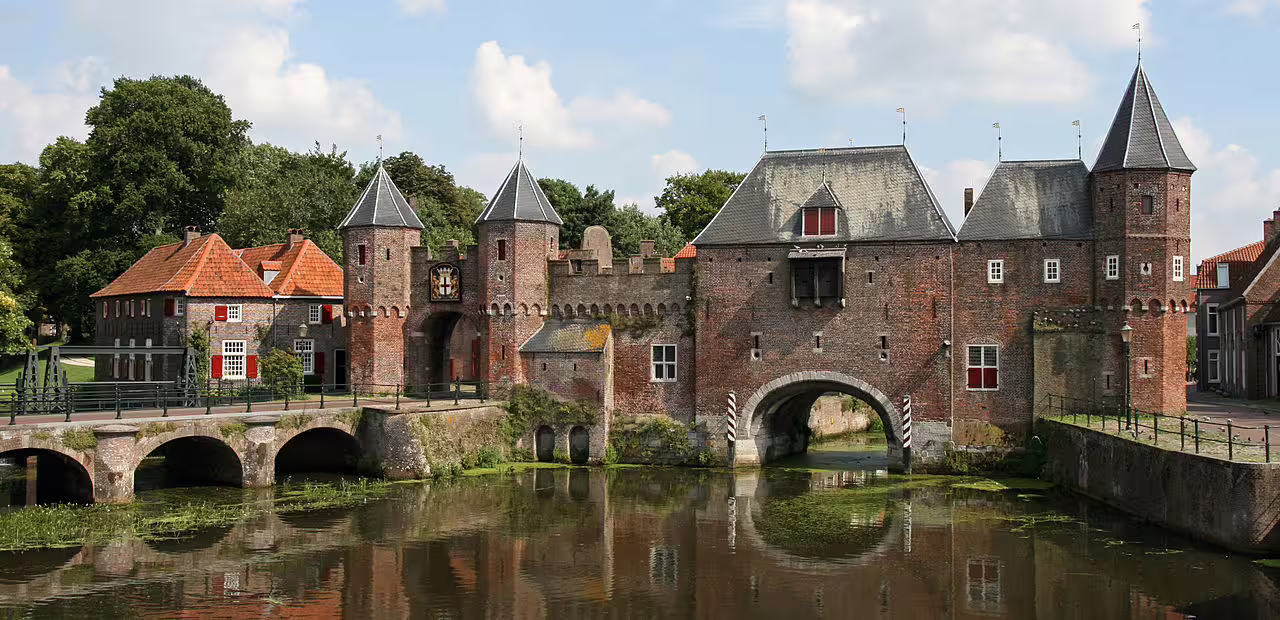 Historic Koppelpoort gate reflected in canal on Amersfoort walking tour, accessible by train from Amsterdam, showcasing medieval architecture.