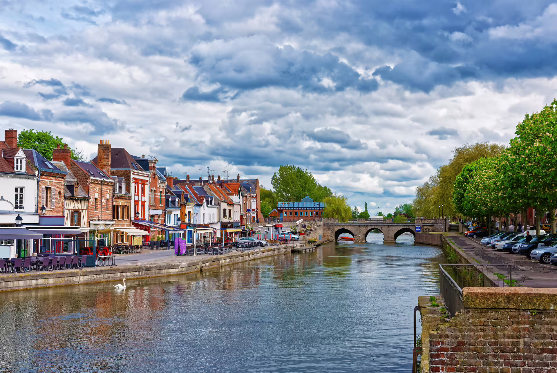 Somme River waterfront in Amiens with colorful houses and stone bridge, highlight of 1-day audioguide tour