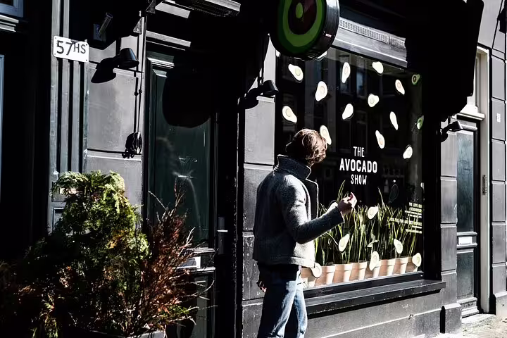 Person walking past The Avocado Show in Amsterdam, showcasing trendy street art and vibrant urban culture on the Amstagram Tour.