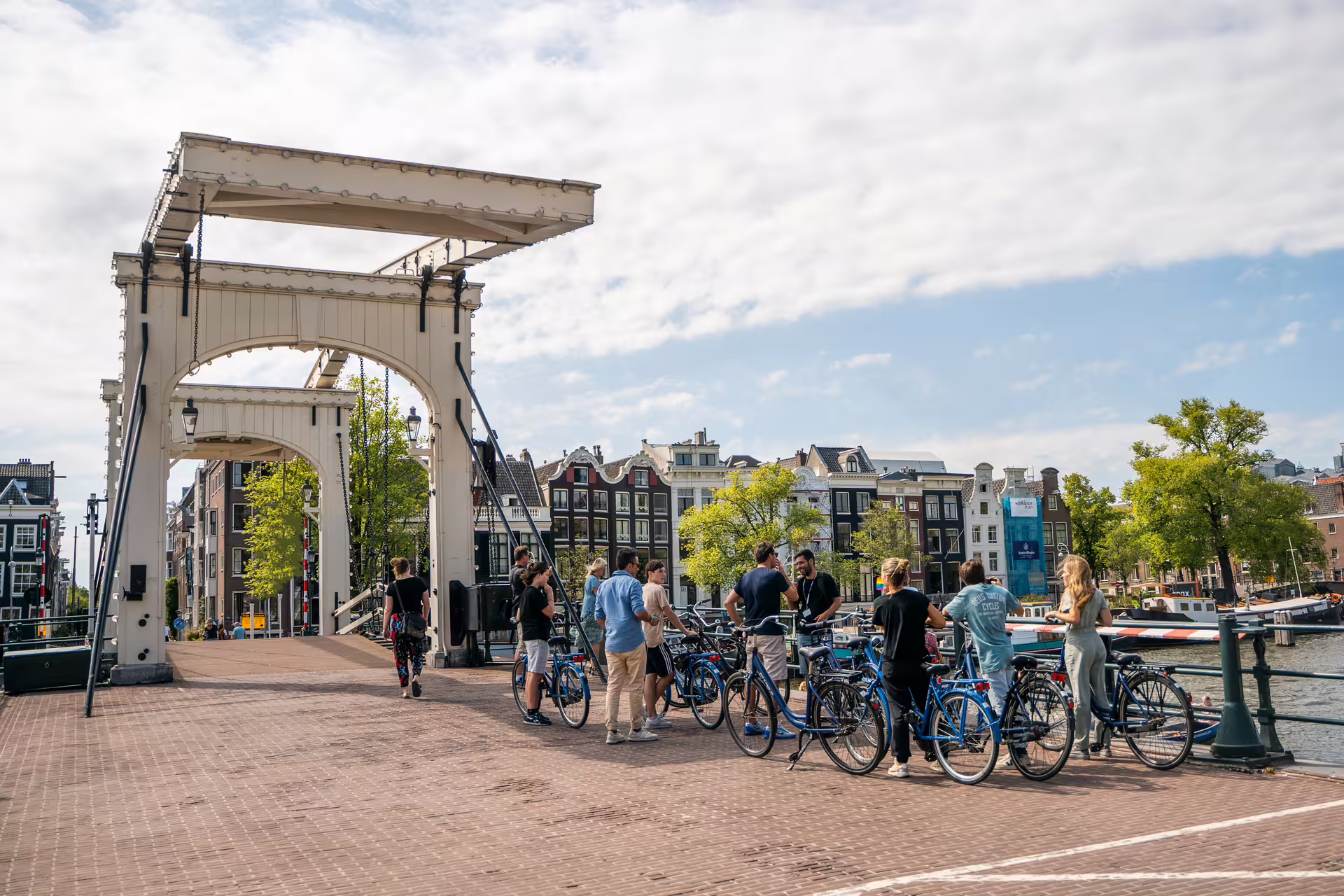 Bicyclists gather on a scenic bridge in Amsterdam during a small group bike tour, exploring the city's charming canals and architecture.
