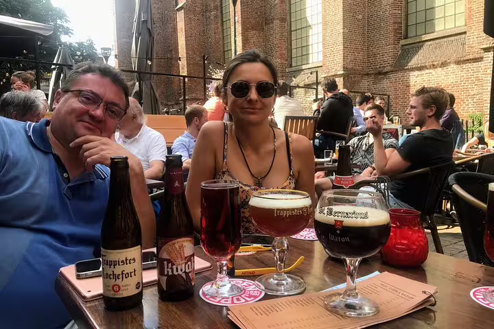 Cyclists enjoying local Dutch craft beers at a canal-side terrace stop during a private Amsterdam hidden gems bike tour