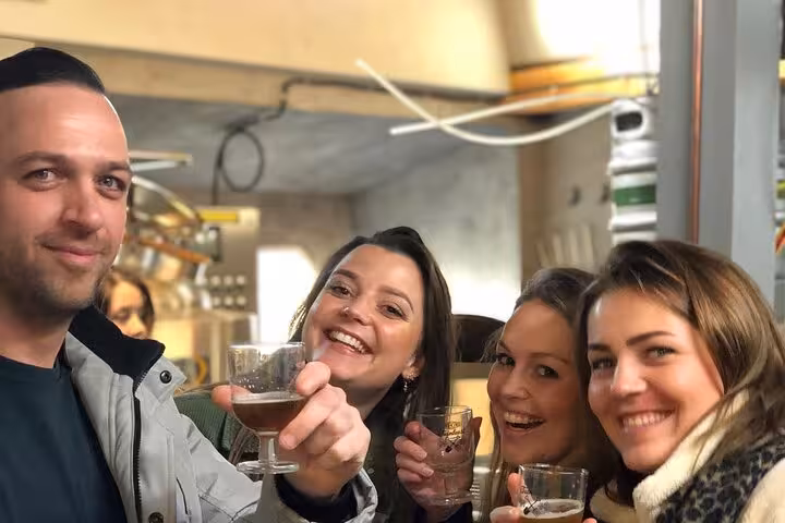 Friends raise craft beer glasses during an Amsterdam brewery tour tasting inside a local brewhouse