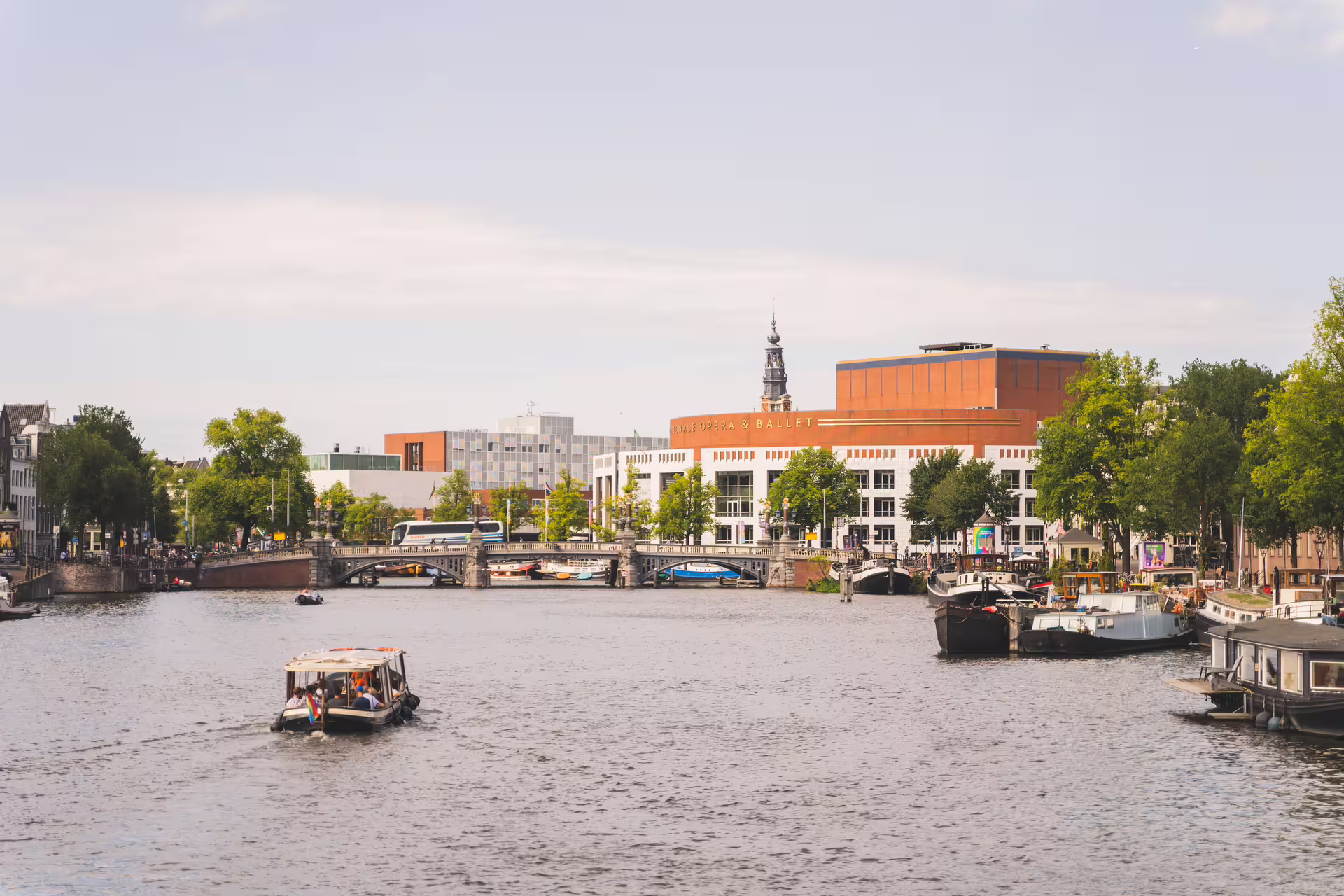 A scenic view of Amsterdam's canal with boats and historic architecture, perfect for a countryside bike tour and canal cruise.
