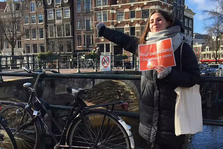 Local guide by Amsterdam canal houses with bike, ideal for a 19th century Amsterdam guided private bike tour