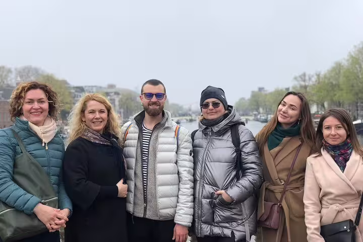 Small group poses by Amsterdam canal during Amsterdam’s Unexpected Treasures private walking tour experience