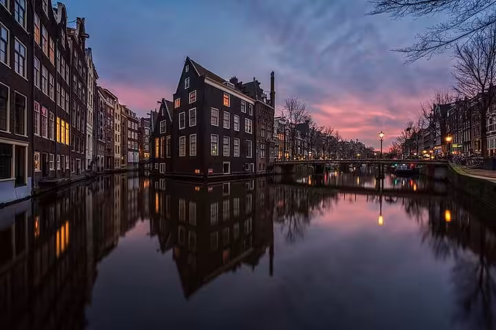 Amsterdam canal houses at dusk near De Wallen, scenic backdrop for a private Red Light District walking tour