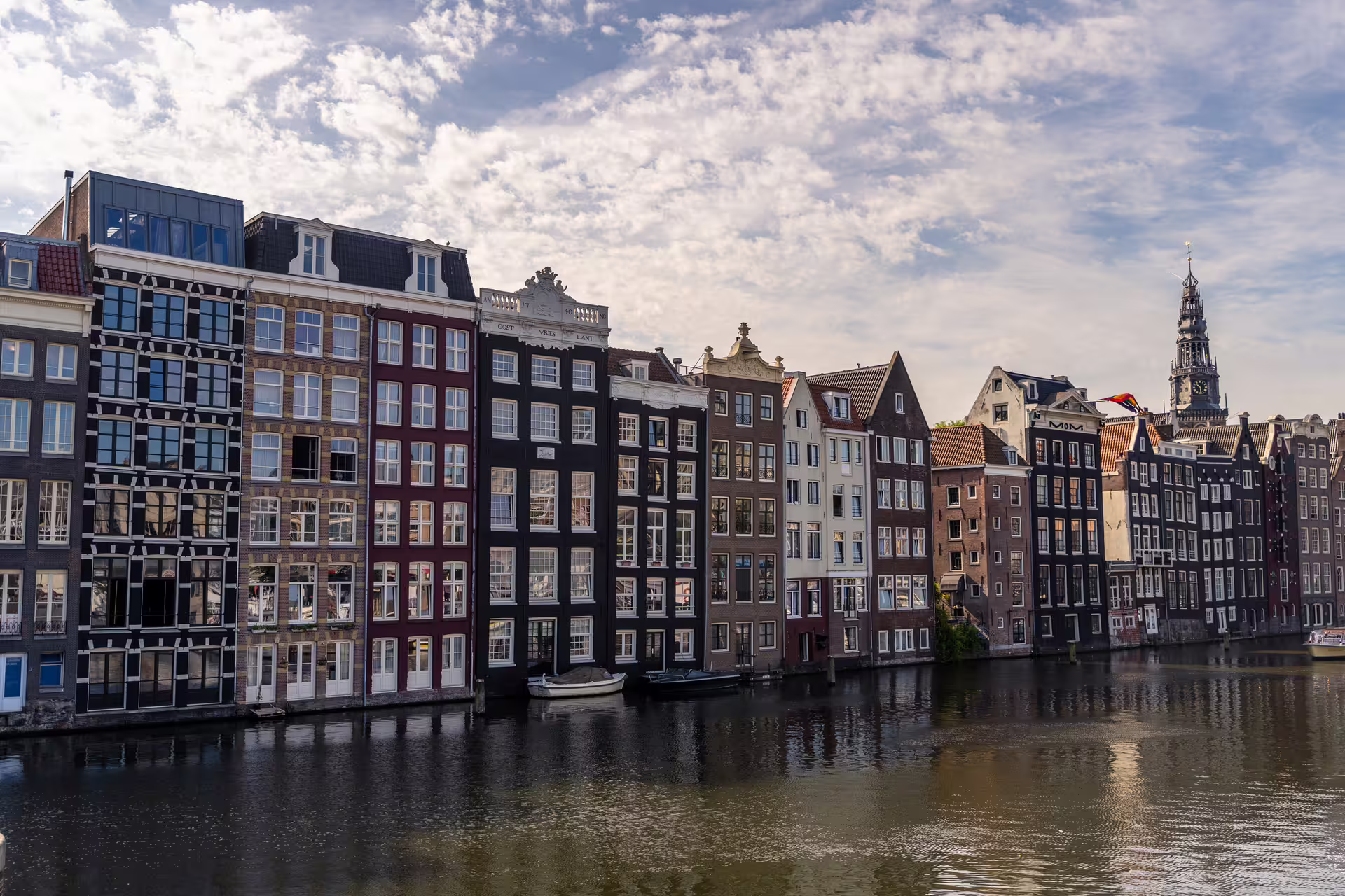 Scenic view of Amsterdam's iconic canal houses under a blue sky, part of the walking tour with cheese tasting experience.