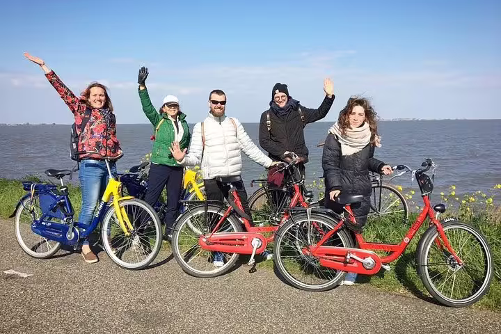 Private guided countryside bike tour from Amsterdam with friends posing by the IJsselmeer lake on Dutch cycle path