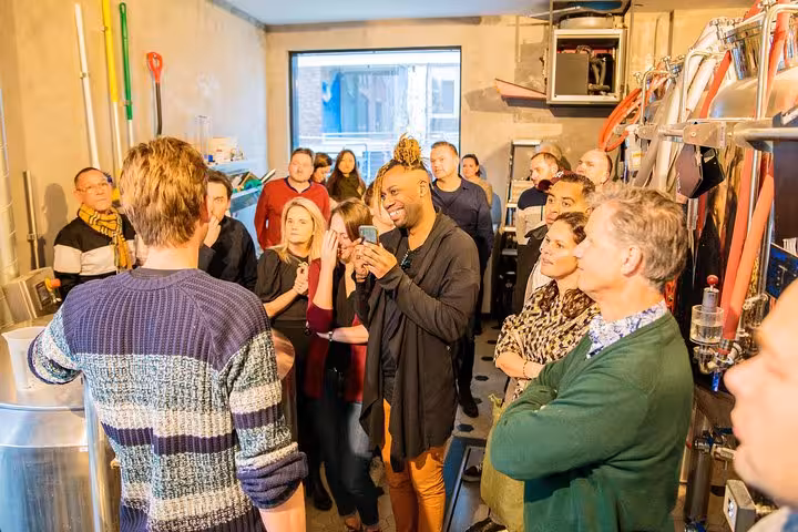 Group listening to brewer at Amsterdam craft brewery during bus beer tour, guided tasting and brewery visit