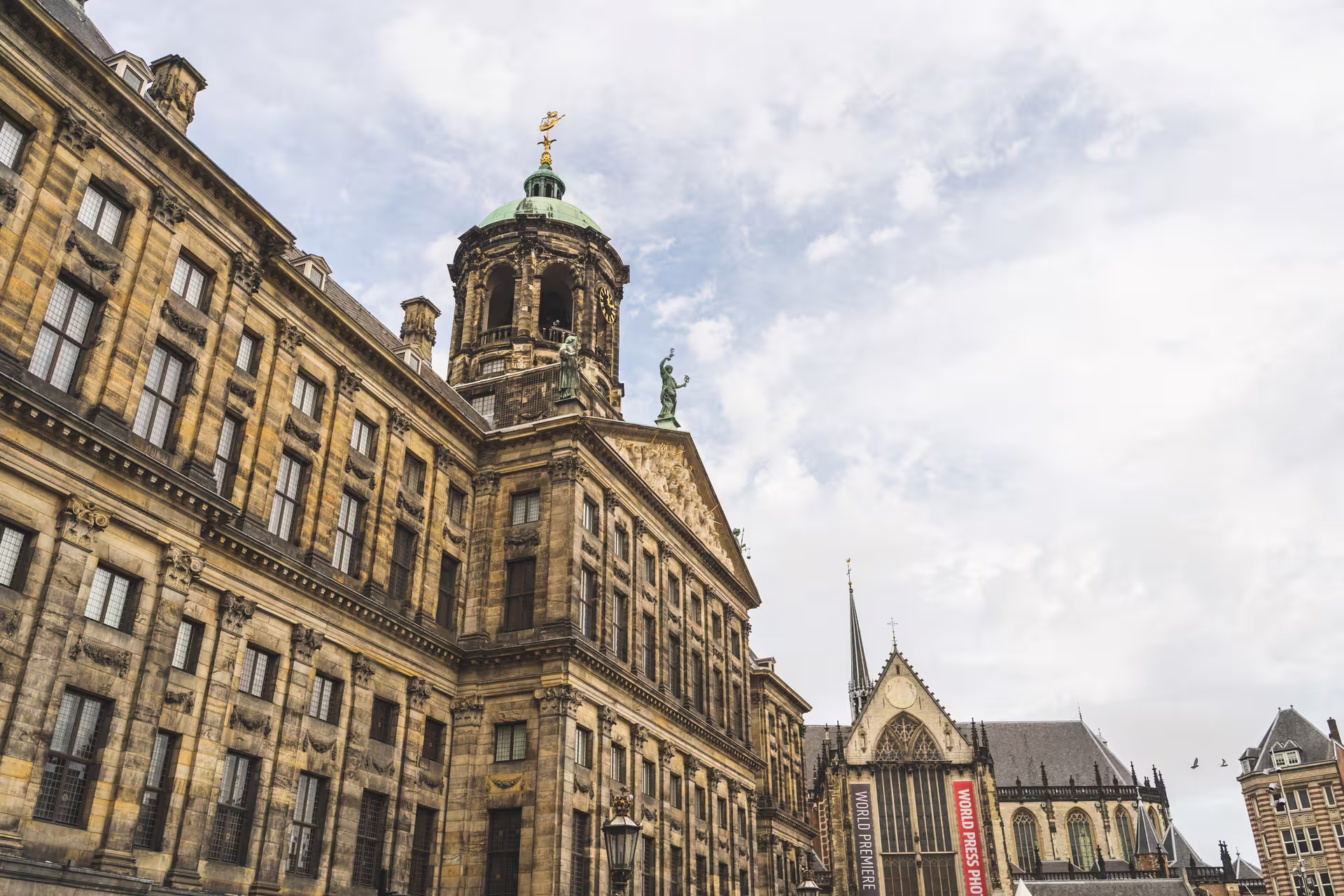 Historic architecture in Amsterdam's Dam Square, featuring the Royal Palace and Nieuwe Kerk, highlights of a walking tour with cheese tasting.