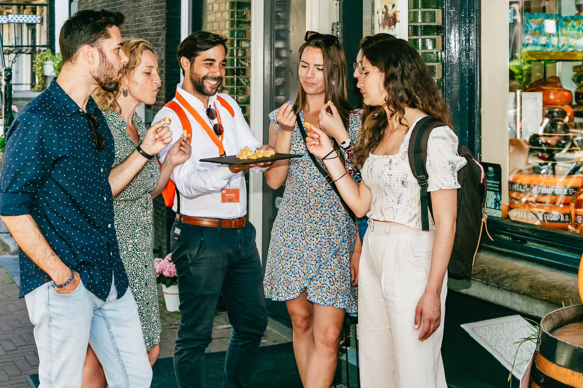 Tourists enjoy a guided food tasting in Amsterdam, sampling local cheese during the Secrets of Historical Amsterdam tour.