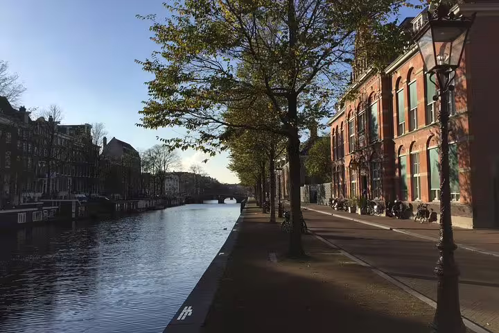 Scenic view of Amsterdam's Jewish Quarter canal with historic architecture and tree-lined paths, ideal for private guided tours.