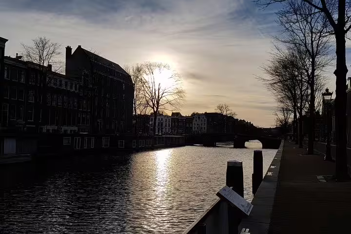Scenic view of Amsterdam's Jewish Quarter at sunset, featuring tranquil canal and historic architecture on a private tour.