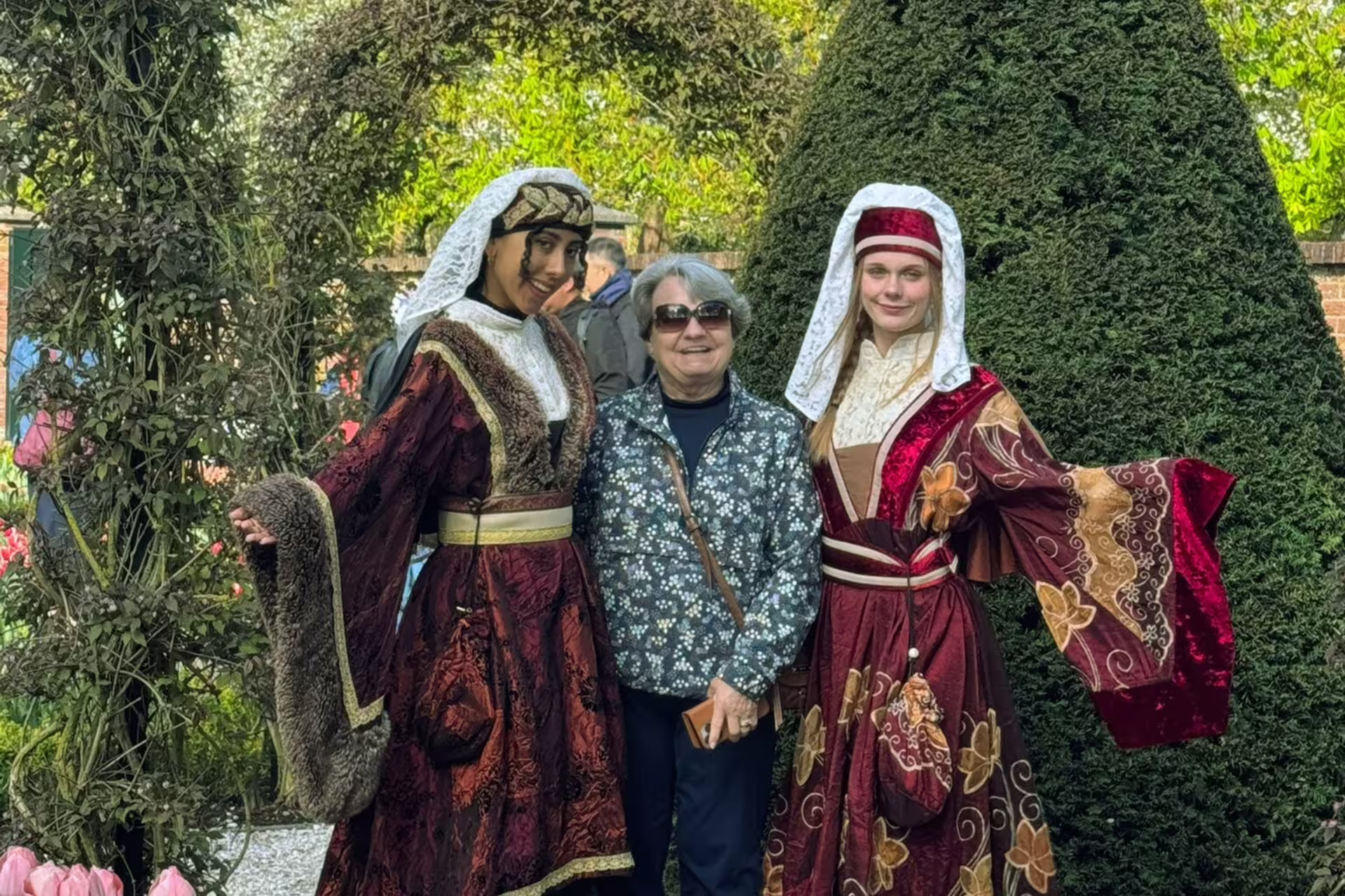 Tour guests pose with performers in traditional Dutch costumes during Keukenhof visit from Amsterdam day tour