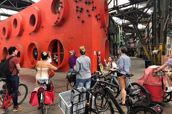 Cyclists on a private guided Amsterdam Noord bike tour by the red NDSM art building in an industrial hall
