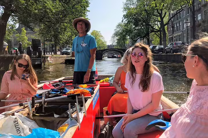 Small group on Amsterdam canal boat near a bridge, local guide sharing hidden gems on private tour