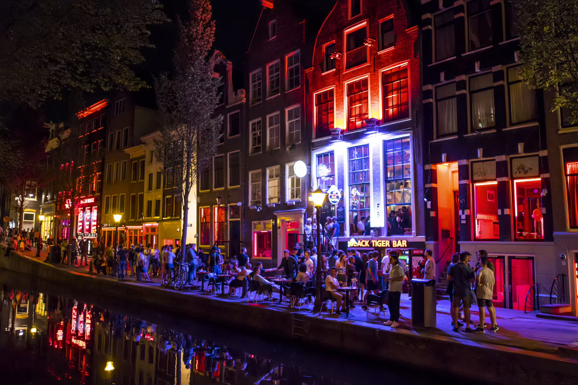 Canal-side nightlife in Amsterdam Red Light District with red windows and bars on a 1-day audio walking tour