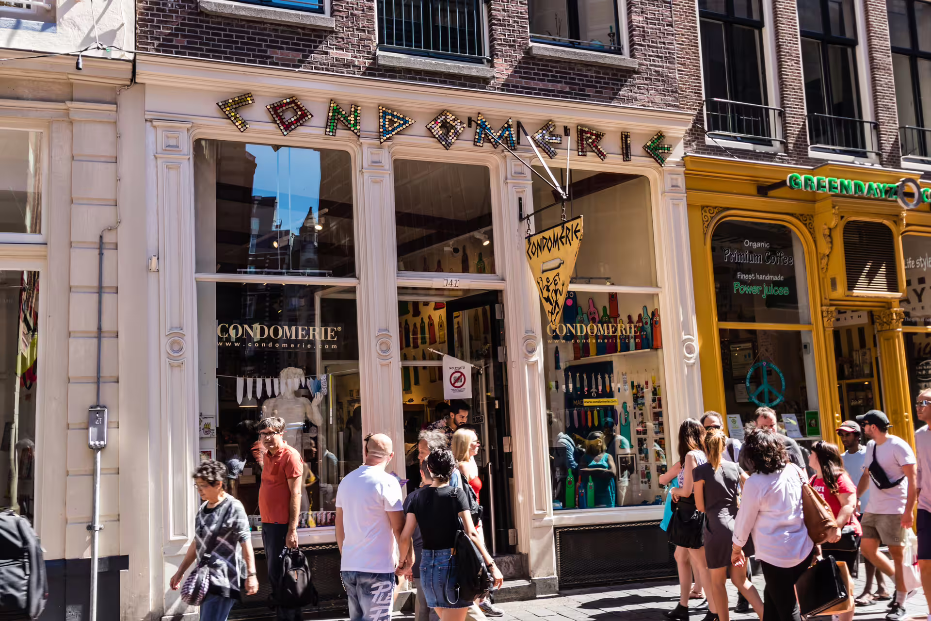 Crowds passing the Condomerie storefront in Amsterdam Red Light District, featured on 1-day audioguide walking tour