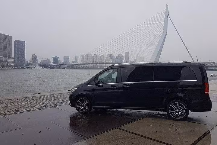 Luxury black minivan by Amsterdam waterfront, private transfer to Schiphol Airport with comfort service