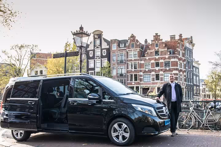 Private chauffeur greeting beside luxury van in Amsterdam for Schiphol Airport to Utrecht door-to-door transfer