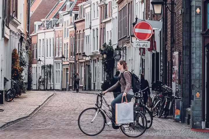 Cyclist on cobbled Dutch street in Amsterdam, ideal for Amsterdam to Utrecht private transfer from Schiphol