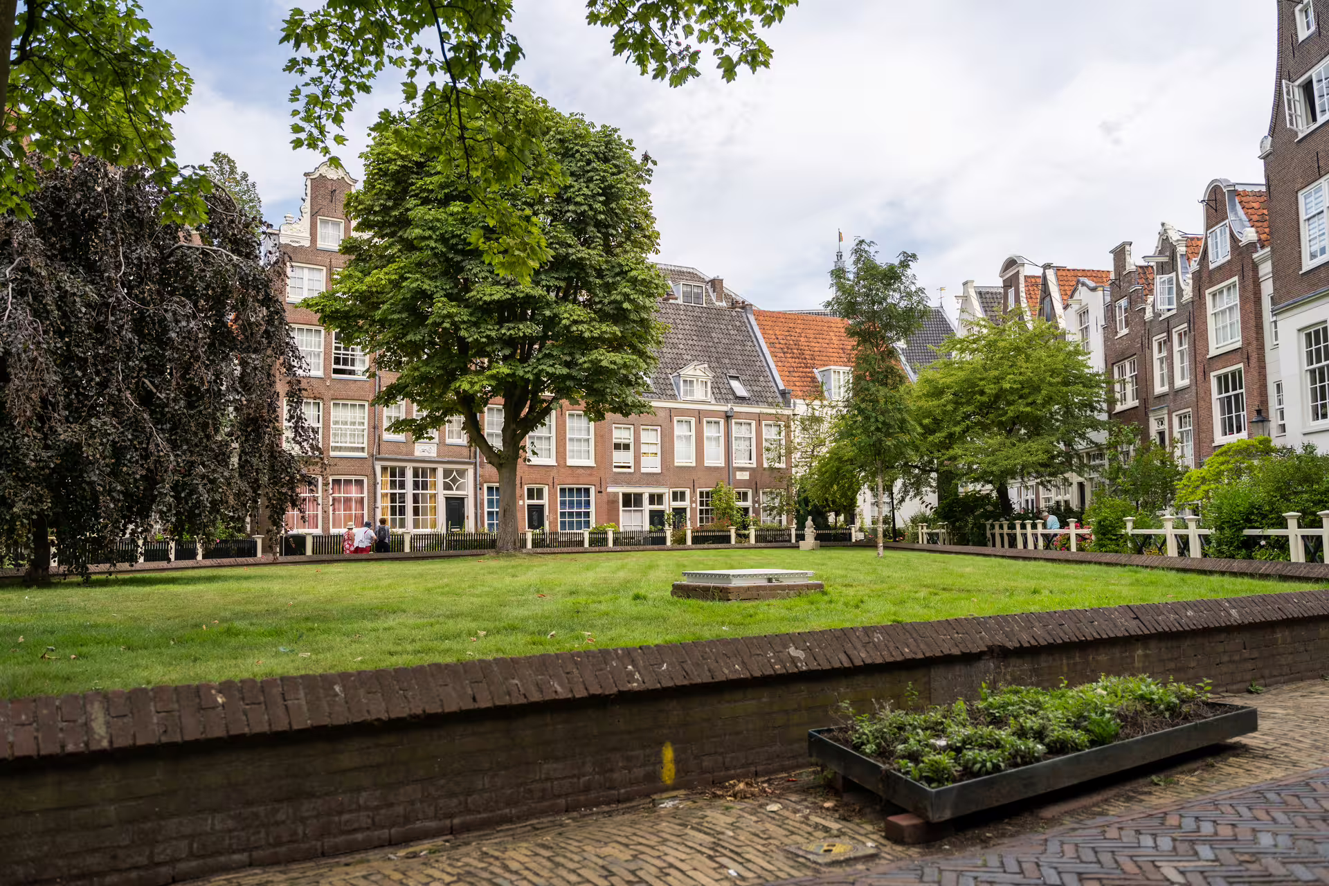 Scenic Amsterdam courtyard with historic buildings and lush greenery, perfect for a walking tour with cheese tasting experience.
