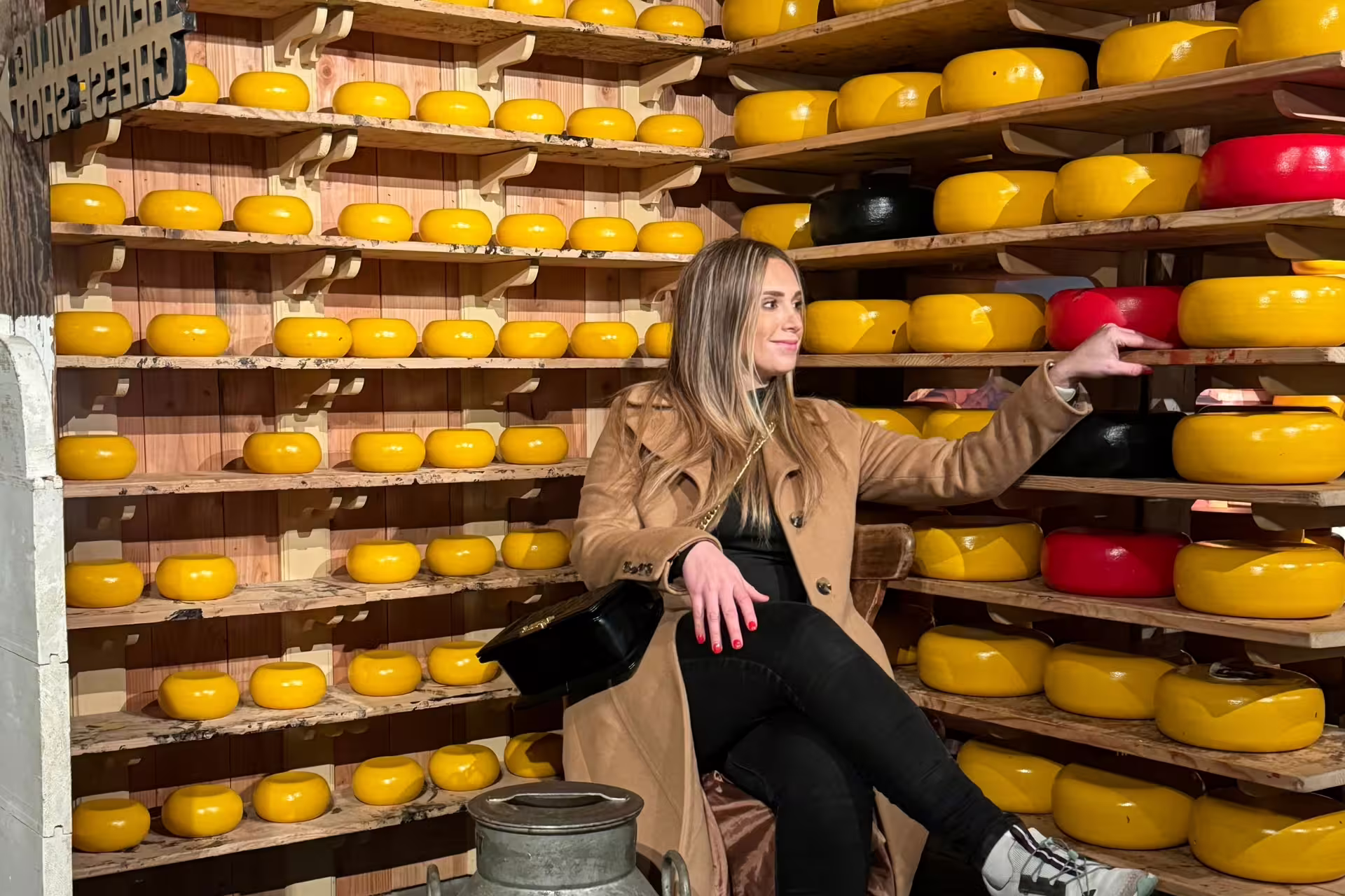 Visitor in Zaanse Schans cheese barn surrounded by Gouda wheels on Amsterdam day trip with canal cruise