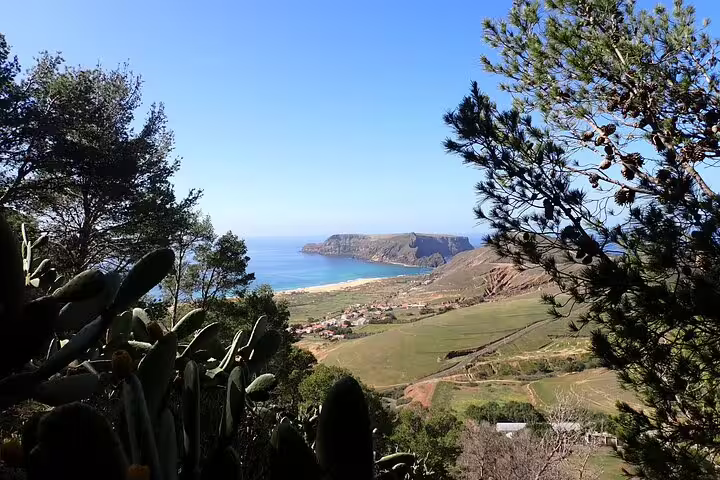 Scenic view of Ana Ferreira Caves & Peaks Trek with lush greenery, rugged coastline, and clear blue ocean on a sunny day.