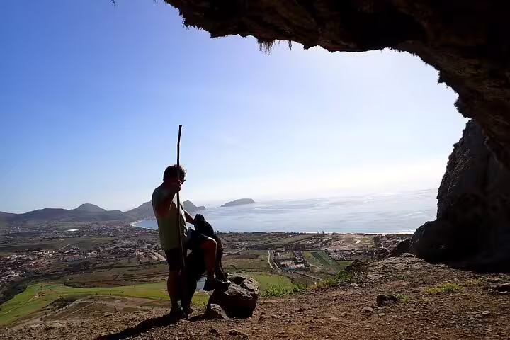 Hiker explores Ana Ferreira Caves with stunning ocean and peak views, perfect for adventurous treks on Porto Santo Island.