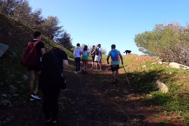 Hikers explore rugged terrain at Ana Ferreira Caves & Peaks Trek, showcasing stunning natural formations under a clear blue sky.