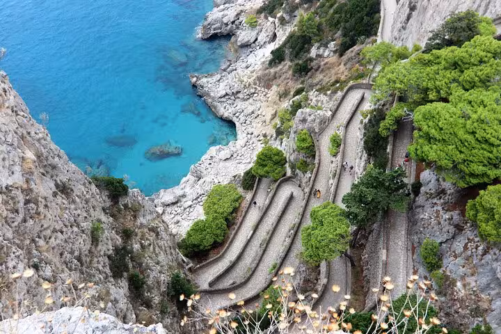 Aerial view of Anacapri's winding paths along the cliffs with emerald sea below, showcasing natural beauty of Capri tours.