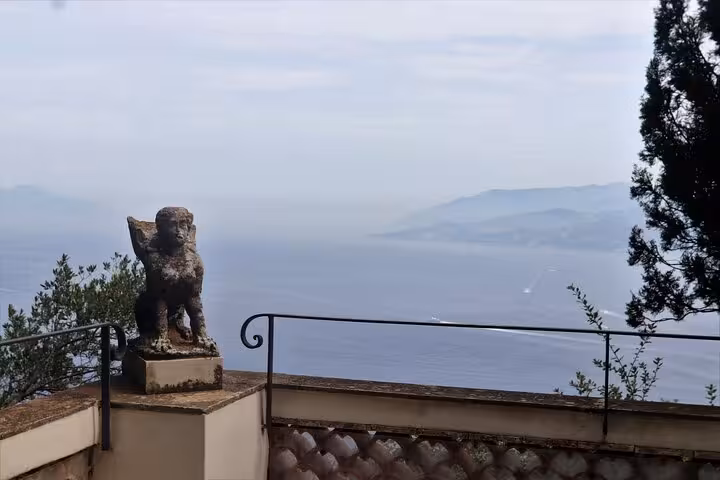 Stunning Anacapri terrace view overlooking the azure sea with a historic statue, ideal for a Capri and Anacapri tour.