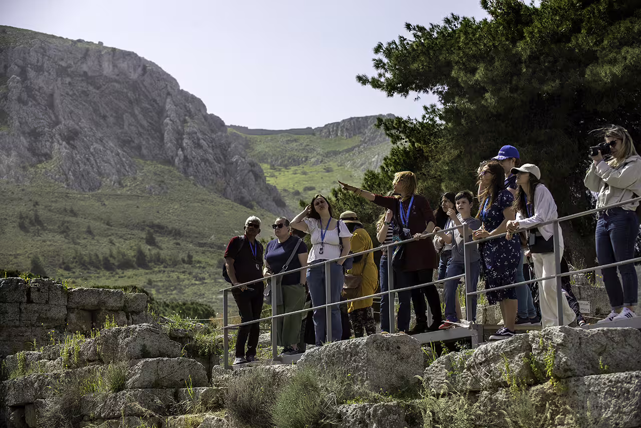 Guided group exploring Ancient Corinth ruins with mountains backdrop on full-day Corinth and Nafplion tour