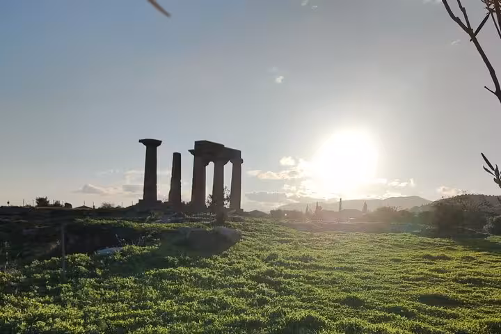 Sunset over Ancient Corinth temple columns and green fields, atmospheric moment on a Biblical Corinth wine and olive oil tasting tour