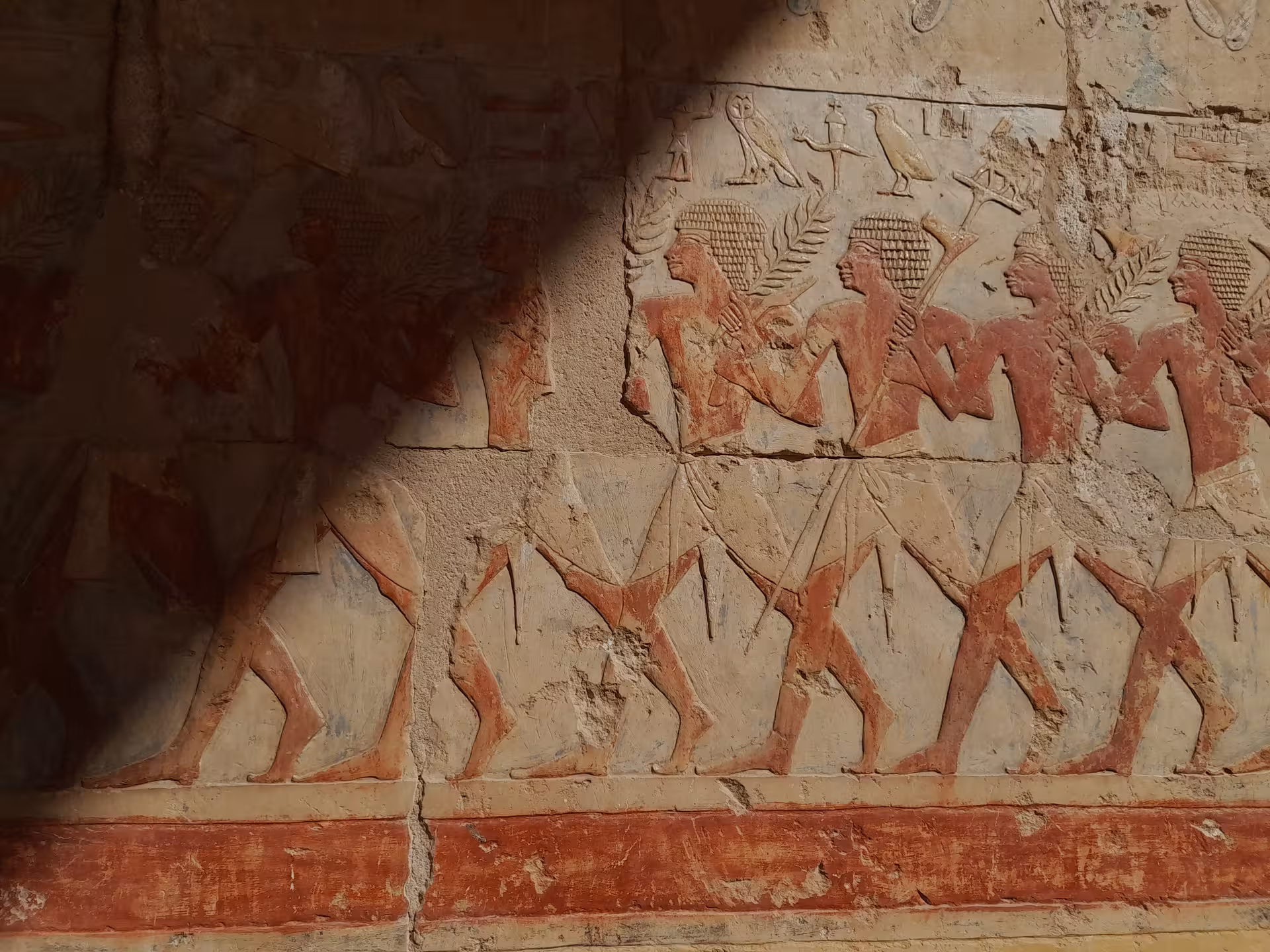 Ancient Egyptian wall carvings depicting figures in procession, showcasing historical art and culture in Egypt.