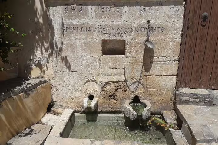 Historic stone fountain with ancient Greek inscriptions in a quaint village on the South Coast of Crete, ideal for cultural exploration.