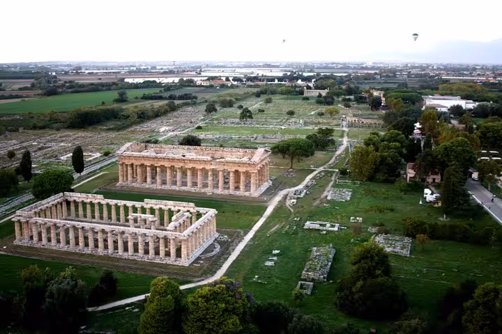 Aerial view of ancient Greek temples surrounded by lush greenery in Paestum, featured on the private tour from Sorrento.