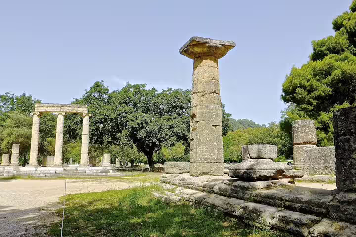Ruins of the ancient Olympia, Greece, showcasing historical columns amidst lush greenery.