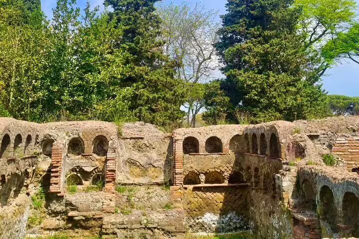 Ancient Ostia Antica brick ruins surrounded by lush trees, visited on exclusive boat river cruise and guided tour from Rome