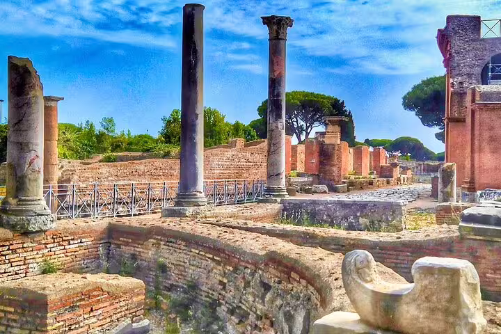 Sunlit ruins and standing columns of Ancient Ostia Antica archaeological site visited on river cruise tour from Rome