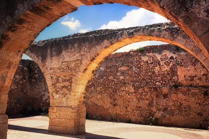Ancient stone arches of a historic Cretan ruin illuminated by sunlight, highlighting Chania's rich architectural heritage.
