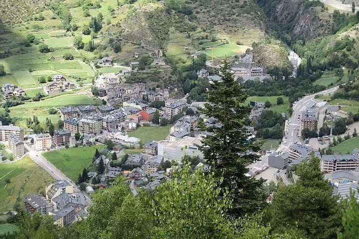 Aerial view of lush green valley and charming village in Andorra, perfect for exploring nature and culture.