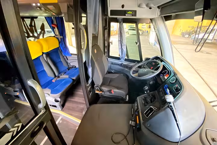 Interior view of a modern bus driver's seat and controls, showcasing the comfort and technology for the Angra dos Reis to Paraty shuttle.