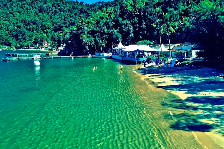 Scenic view of a tranquil beach with clear turquoise waters and lush greenery in Angra dos Reis, ideal for private boat tours.