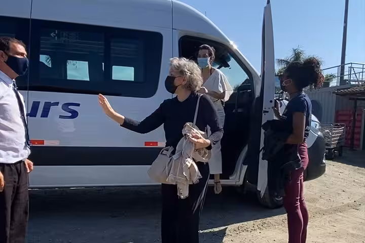Passengers with masks exit a van during a shared transfer from Angra dos Reis to Rio de Janeiro, ensuring safe travel.